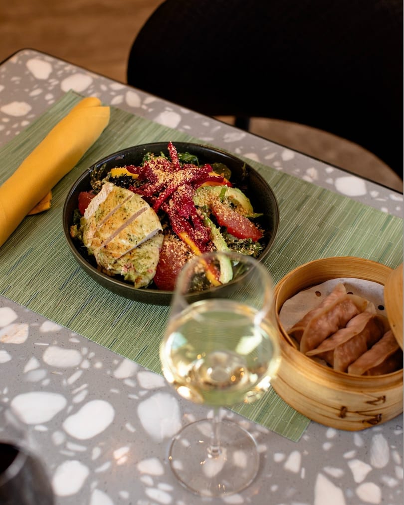 Grilled chicken salad with avocado, grapefruit, and beets, alongside dumplings and white wine.